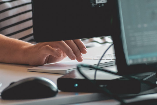 Close-up of a hand sitting in front of a PC and its keyboard, hovering just above an external touchpad.