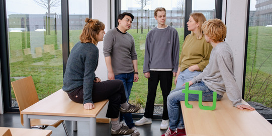 Ein Gruppenfoto von Studierenden im Seminarraum mit dem TU Dortmund Logo.